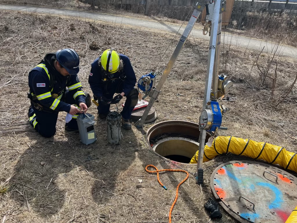 2 people preparing to enter a manhole