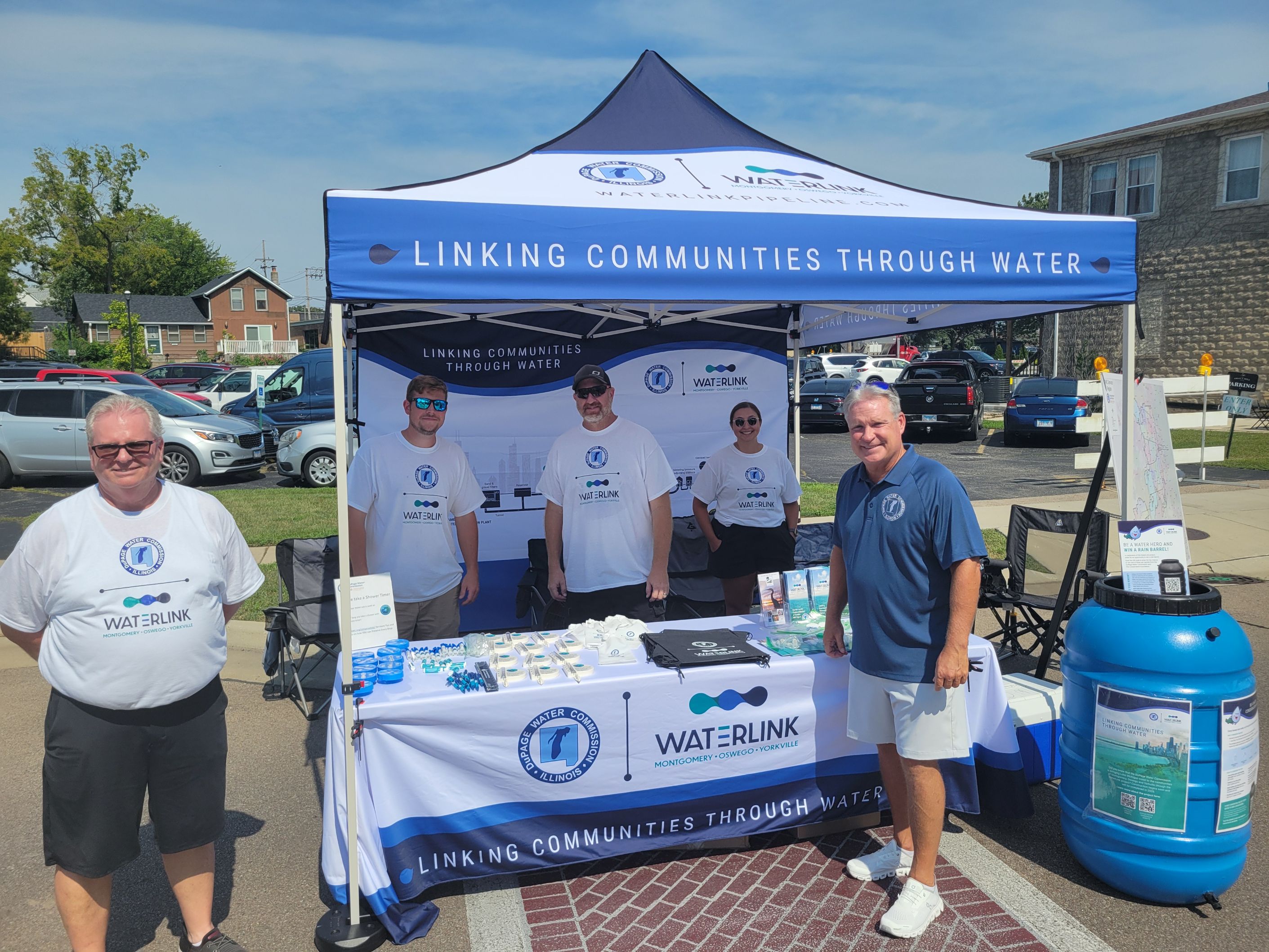 people standing at a table at a festival handing out information on Waterlink