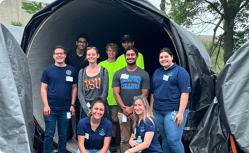 9 people standing in a large empty pipe